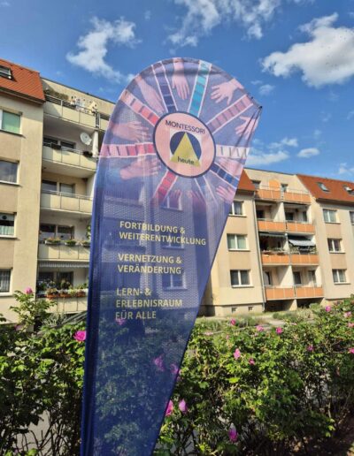 Strandfahne im Außenbereich mit dem Logo von MONTESSORIheute