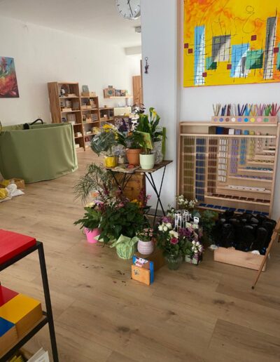 Regal mit Montessori-Materialien und Blumen-geschenken