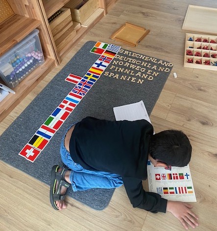 Kind arbeitet in der DaZ-Förderung mit Montessori-Flaggenmaterial
